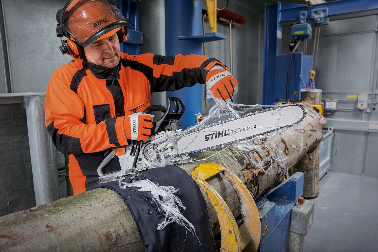Uma pessoa testa a proteção contra cortes do vestuário de proteção STIHL enquanto usa uma motosserra STIHL