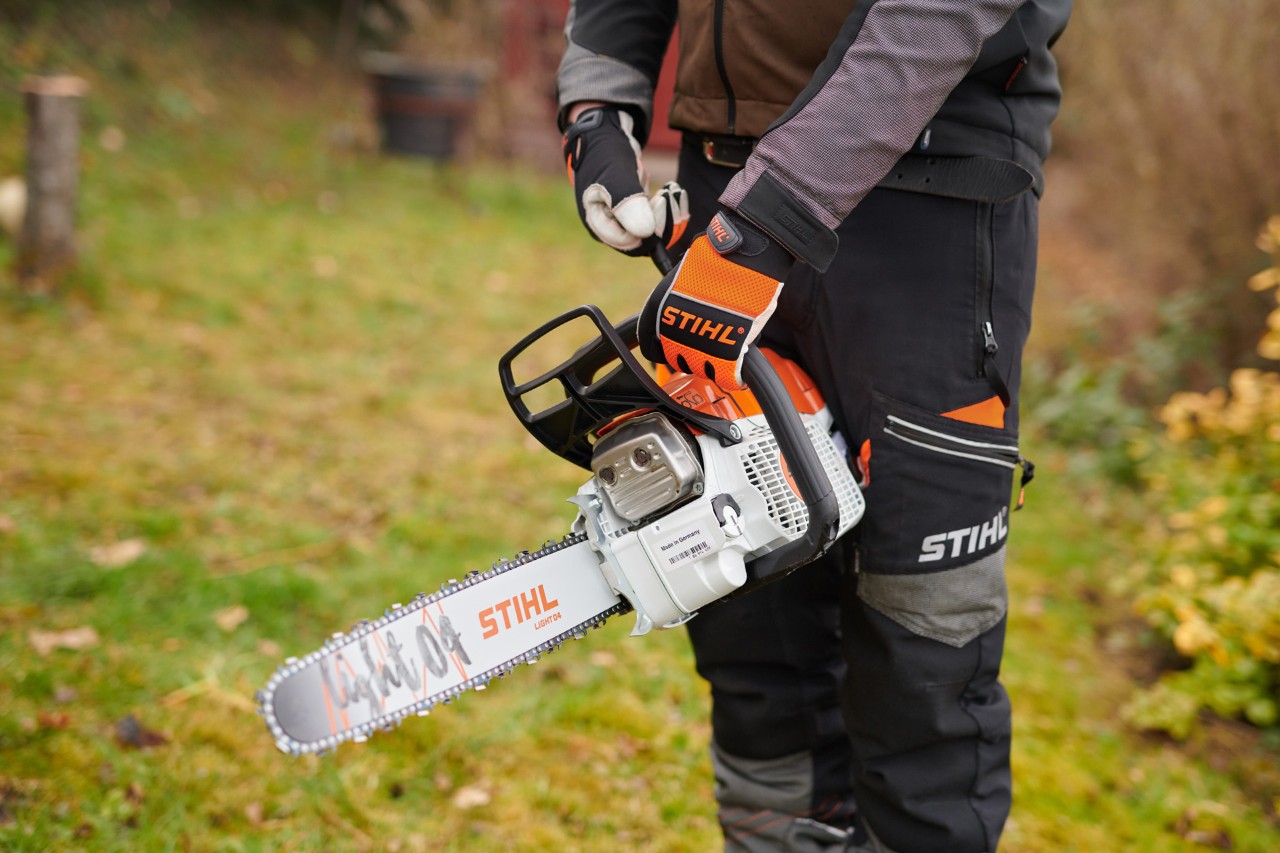 Um homem com equipamento de proteção a segurar uma motosserra a gasolina com o sistema STIHL ElastoStart e guia Light 04