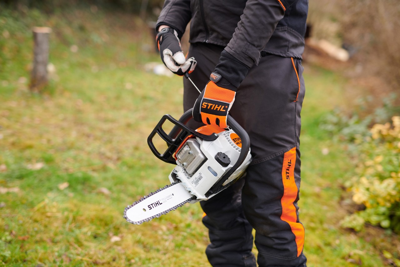 Uma motosserra STIHL 180 C-BE a gasolina com o sistema STIHL ErgoStart manuseada por pessoa com equipamento de proteção