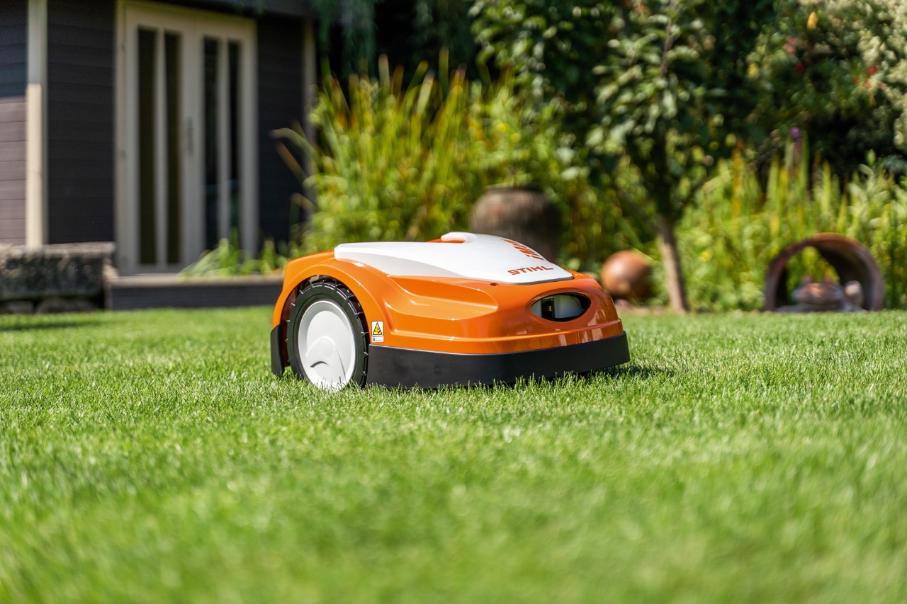Um robot corta-relva STIHL iMOW® RMI 422 num relvado verde à frente de uma casa