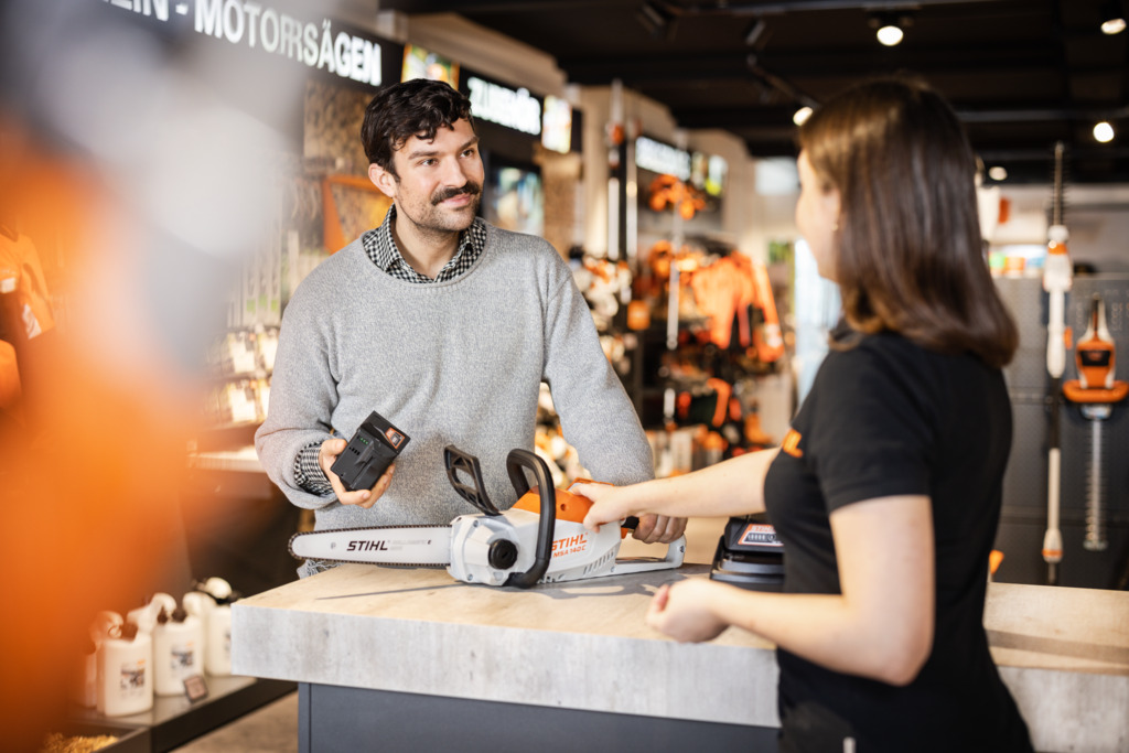 O revendedor mostra ao cliente a motosserra a bateria