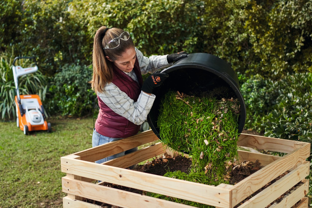 Mulher a despejar composto num compostador