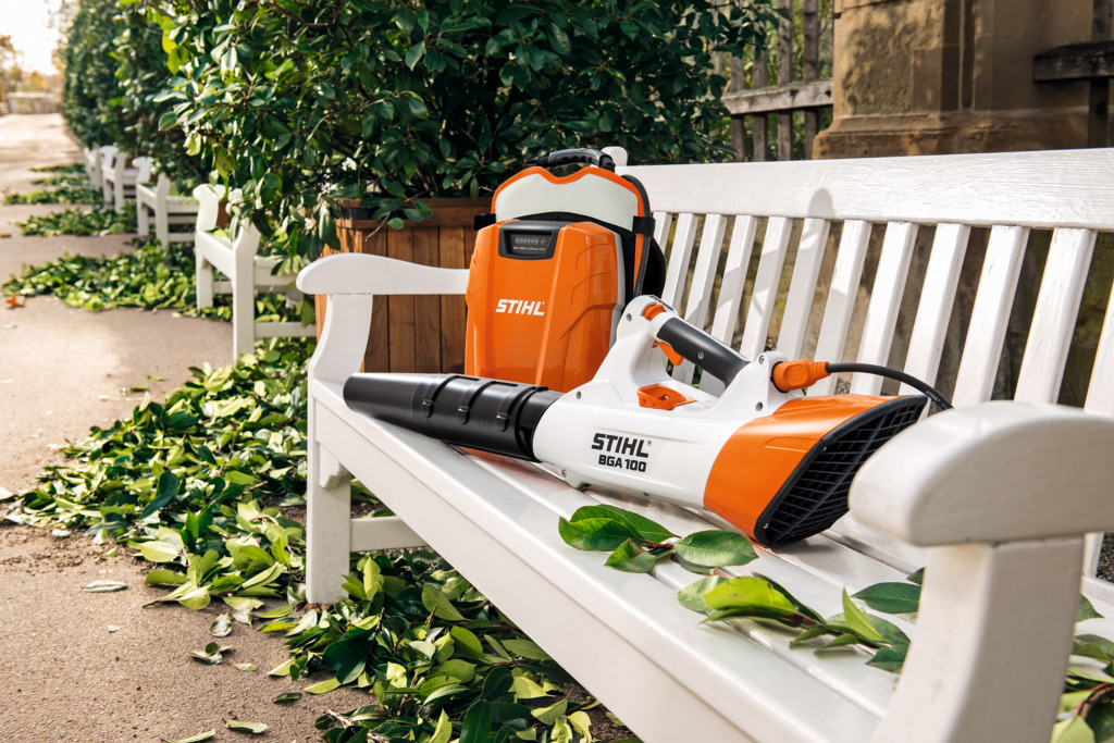 Soprador de folhas BGA 100 STIHL e uma bateria de costas num banco de jardim