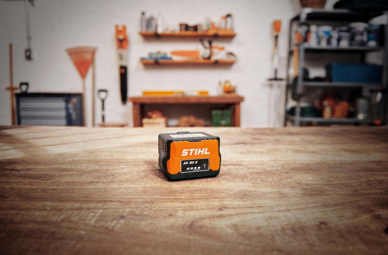 Oficina com uma bateria STIHL AK 30 S numa mesa de madeira 